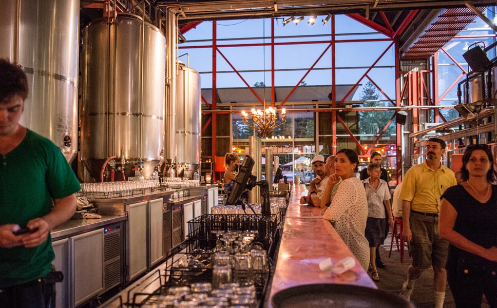 Man kann es sich auch in der umgebauten Lagerhalle bequem machen, am Tresen oder an einem der vielen Tische, dem Pizzabäcker am Holzbackofen oder den Köchen in der offenen Küche zuschauen, angesagte Musik hören und natürlich ein Bier trinken.